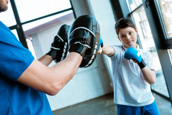 Boy in boxing gloves working out with coach at gym — Stock Photo