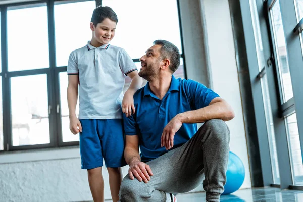 Padre e figlio sorridenti si guardano l'un l'altro al centro sportivo — Foto stock