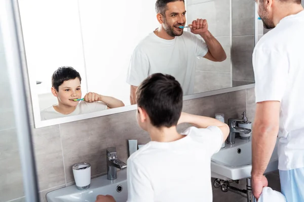 Father and son brushing teeth in bathroom in morning — Stock Photo