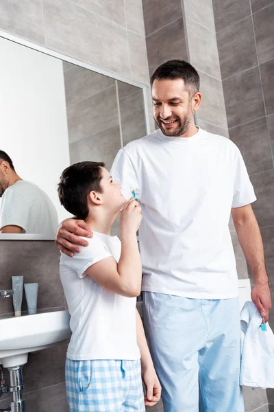 Sorrindo pai e filho com escovas de dentes no banheiro — Fotografia de Stock