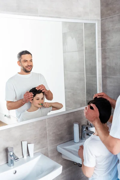 Sorrindo pai ajustando penteado do filho no banheiro de manhã — Fotografia de Stock