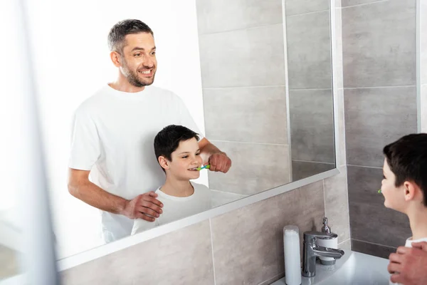 Father brushing teeth of son in bathroom during morning routine — Stock Photo