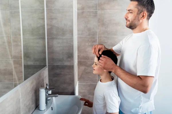 Padre ajustar el peinado del hijo en el baño por la mañana - foto de stock