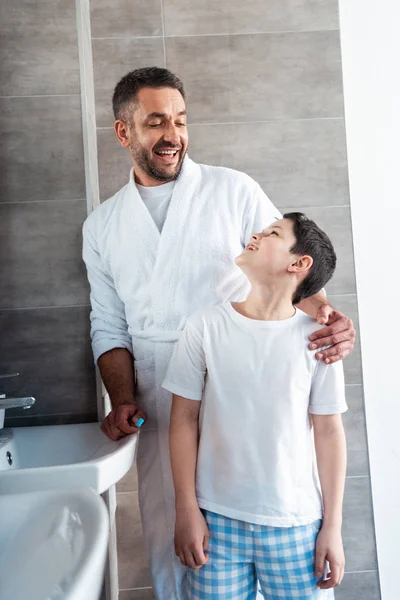 Glücklicher Vater umarmt Sohn im Badezimmer während der Morgenroutine — Stockfoto