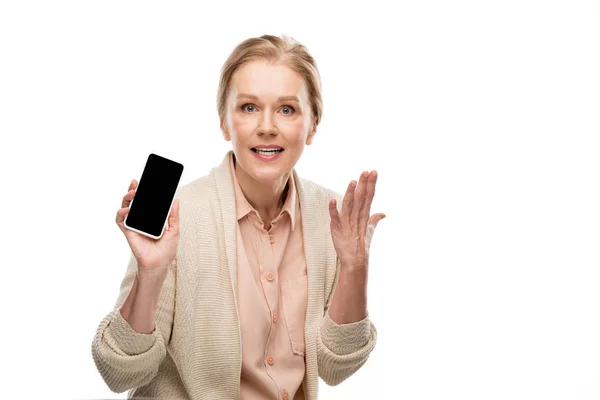 Frau mittleren Alters gestikuliert und zeigt Smartphone mit leerem Bildschirm auf weißem Hintergrund — Stockfoto