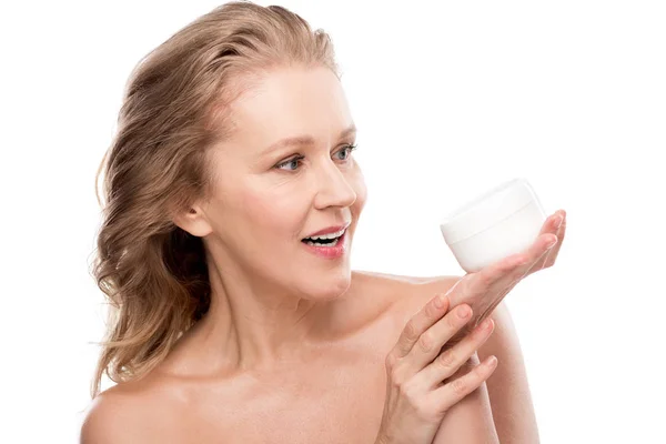 Hermosa mujer madura sosteniendo contenedor con crema cosmética aislado en blanco - foto de stock