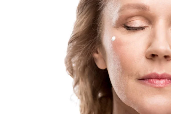 Vista recortada de la mujer madura con crema cosmética en la cara aislado en blanco - foto de stock
