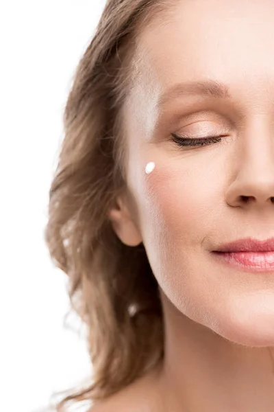 Vue recadrée de femme mature avec crème cosmétique sur le visage isolé sur blanc — Photo de stock