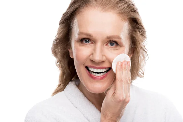 Mature woman wiping face with cotton pad and looking at camera Isolated On White — Stock Photo