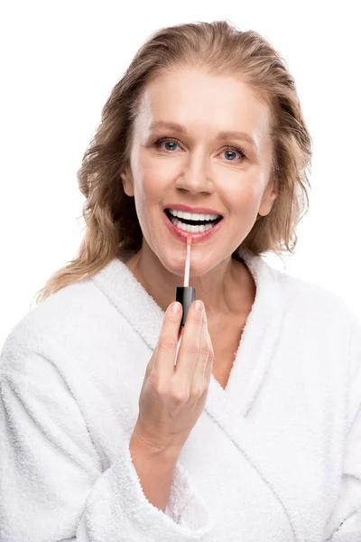 Hermosa sonriente mujer madura aplicando brillo labial aislado en blanco - foto de stock