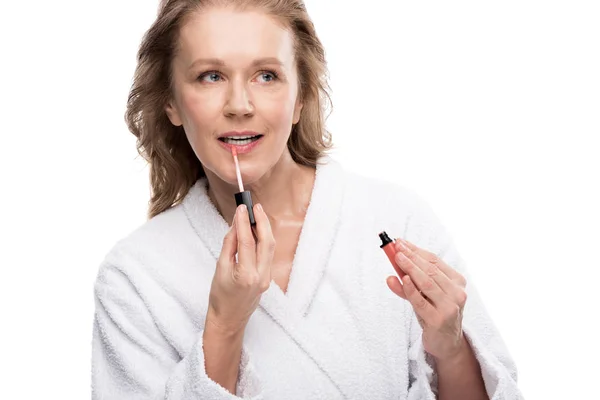 Atraente mulher madura aplicando labial brilho isolado no branco — Fotografia de Stock