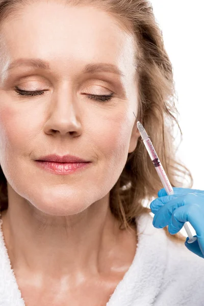 Доктор делает укол красоты женщине средних лет, изолированной от белого — стоковое фото