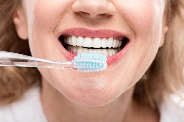 Vista cortada da mulher de meia idade escovando dentes isolados no branco — Fotografia de Stock
