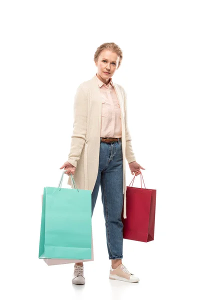 Frau mittleren Alters mit Einkaufstaschen blickt in Kamera auf weiß — Stockfoto