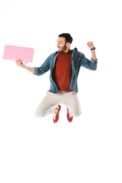 Feliz hombre guapo con el discurso de la burbuja saltando y mostrando el gesto ganador aislado en blanco - foto de stock