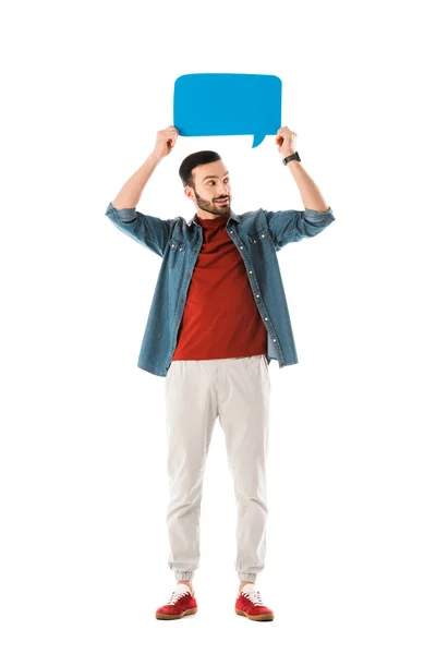 Hombre sonriente en camisa de mezclilla sosteniendo la burbuja del habla y mirando hacia otro lado aislado en blanco - foto de stock