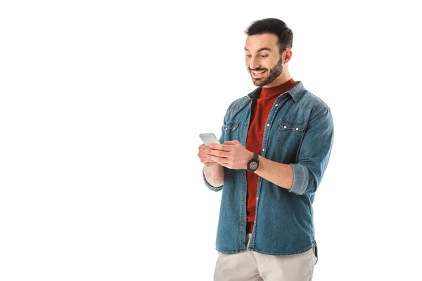 Hombre barbudo alegre sonriendo mientras se utiliza teléfono inteligente aislado en blanco - foto de stock