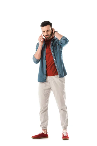 Nachdenklicher bärtiger Mann im Jeanshemd mit Smartphone auf weißem Hintergrund — Stockfoto