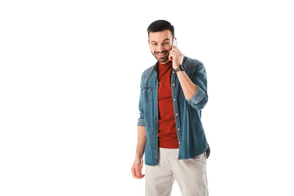 Sonriente guapo en camisa de mezclilla hablando en teléfono inteligente aislado en blanco - foto de stock