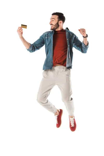 Щасливий чоловік стрибає і показує так жест, тримаючи кредитну картку ізольовано на білому — стокове фото