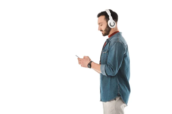 Seitenansicht eines gutaussehenden Mannes mit Kopfhörer, Smartphone isoliert auf weiß — Stockfoto
