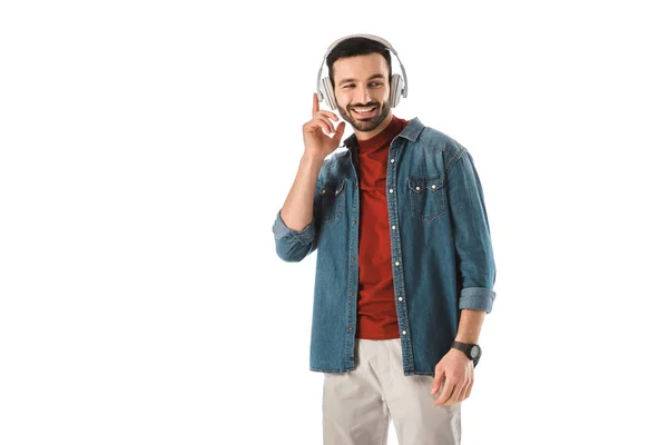 Fröhlicher Mann im Jeanshemd, der mit Kopfhörern isoliert auf weißem Grund Musik hört — Stockfoto