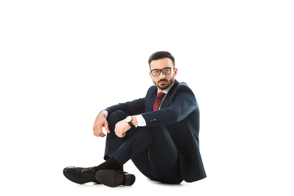 Serious businessman looking away while sitting on white background — Stock Photo