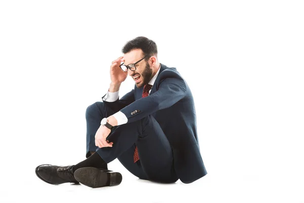 Worried businessman holding hand near head while sitting on white background — Stock Photo