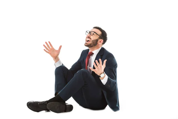 Homem de negócios feliz olhando para cima e gesticulando enquanto sentado no fundo branco — Fotografia de Stock