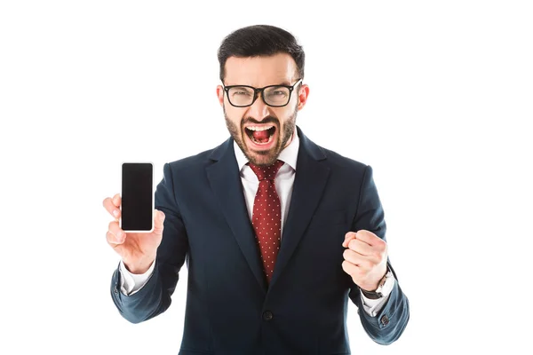 Irritado hombre de negocios peleando y mostrando el puño mientras sostiene el teléfono inteligente con la pantalla en blanco y mirando a la cámara aislada en blanco - foto de stock