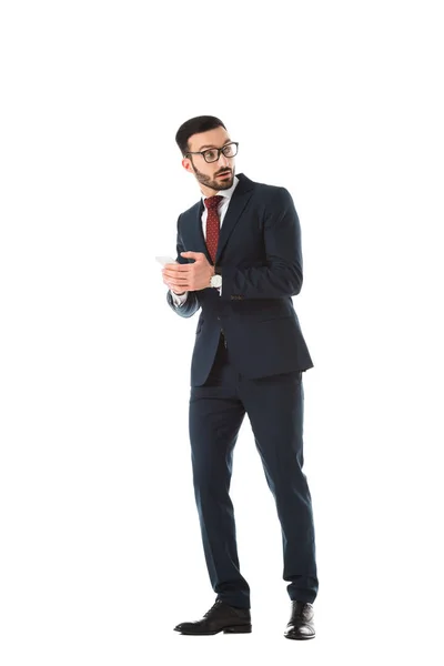 Sorprendido hombre de negocios mirando mientras se utiliza el teléfono inteligente aislado en blanco - foto de stock