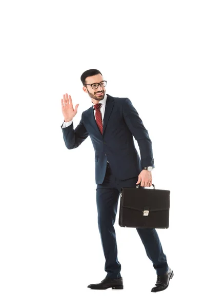 Smiling businessman with briefcase looking back and showing hello gesture isolated on white — Stock Photo