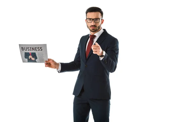 Serious businessman holding businessman holding newspaper and pointing with finger at camera isolated on white — Stock Photo