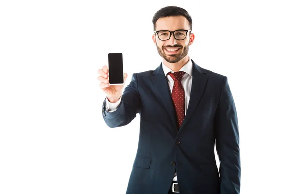 Alegre empresario sosteniendo teléfono inteligente con pantalla en blanco y mirando a la cámara aislada en blanco - foto de stock