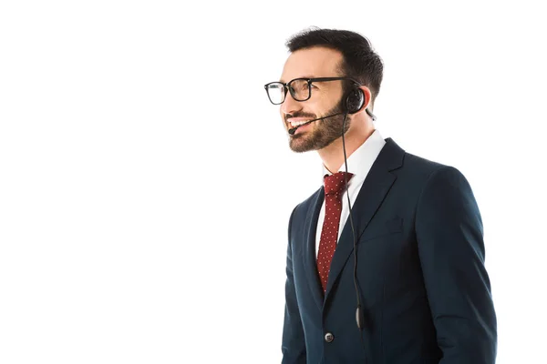 Operador de centro de llamadas guapo en auriculares sonriendo y mirando hacia otro lado aislado en blanco - foto de stock