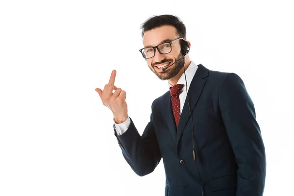 Cheerful handsome call center operator in headset showing middle finger and looking at camera isolated on white — Stock Photo