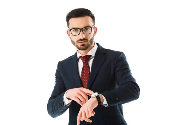 Uomo d'affari fiducioso in occhiali che punta all'orologio e guardando la fotocamera isolata su bianco — Foto stock