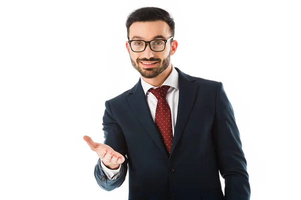 Sonriente hombre de negocios barbudo mirando a la cámara con la mano extendida aislada en blanco - foto de stock