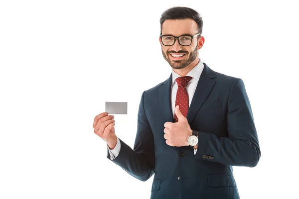 Alegre hombre de negocios sosteniendo la tarjeta de visita en blanco y mostrando el pulgar hacia arriba aislado en blanco - foto de stock