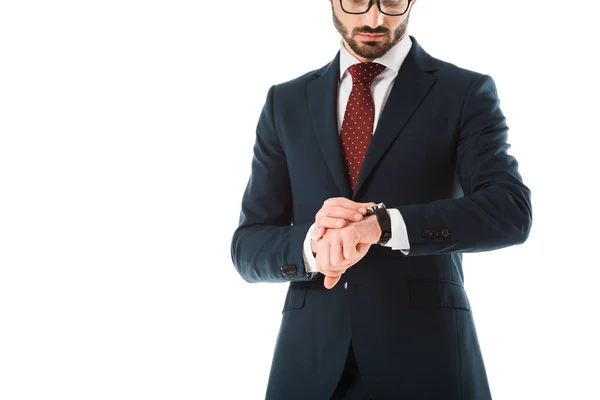 Recortado vista de hombre de negocios en traje negro mirando reloj aislado en blanco - foto de stock