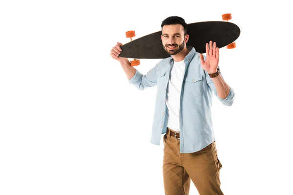 Uomo allegro con longboard guardando la fotocamera e mostrando ciao gesto isolato su bianco — Stock Photo