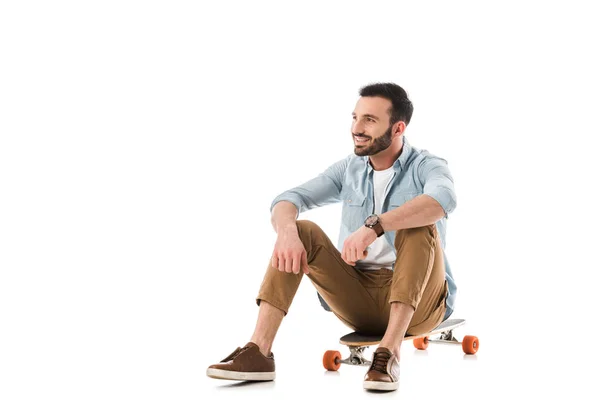 Hombre feliz sentado en longboard y mirando lejos aislado en blanco - foto de stock