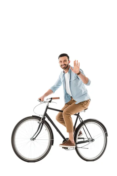 Handsome cheerful man riding bicycle and showing hello gesture at camera isolated on white — Stock Photo