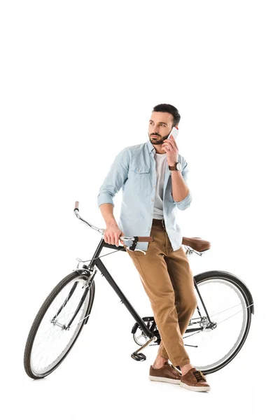 Uomo premuroso con bicicletta che parla su smartphone e distoglie lo sguardo isolato sul bianco — Foto stock