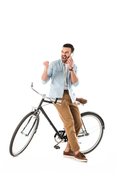 Homme en colère avec vélo querelle et montrant poing tout en parlant sur smartphone isolé sur blanc — Photo de stock