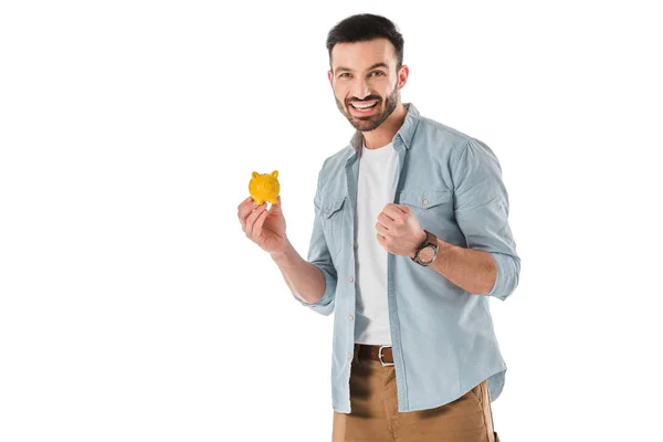 Feliz hombre guapo sosteniendo alcancía y mostrando sí gesto aislado en blanco - foto de stock