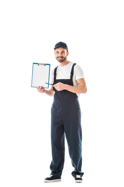 Cheerful delivery man pointing with pen at clipboard with empty paper and looking at camera isolated on white — Stock Photo