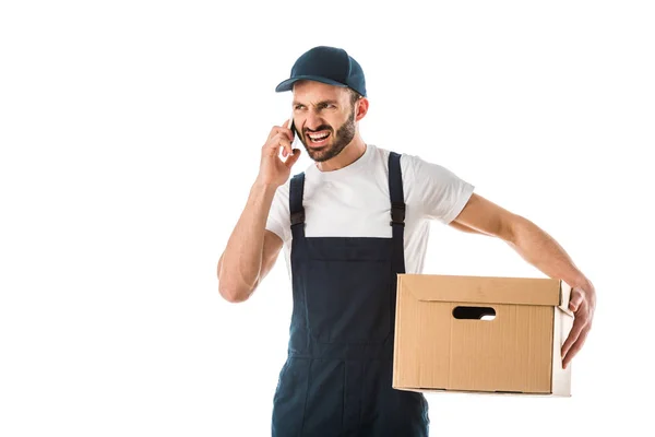Hombre de entrega enojado hablando en el teléfono inteligente mientras sostiene la caja de cartón aislado en blanco — Stock Photo