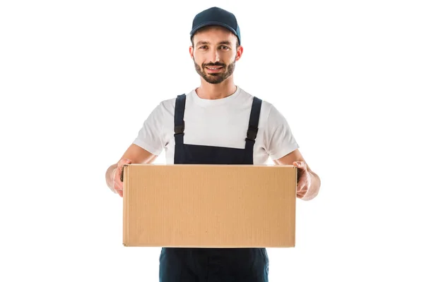 Cheerful handsome delivery man holding cardboard box and smiling at camera isolated on white — Stock Photo