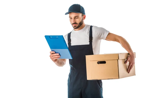 Atento hombre de entrega guapo sosteniendo caja de cartón y mirando portapapeles aislado en blanco - foto de stock